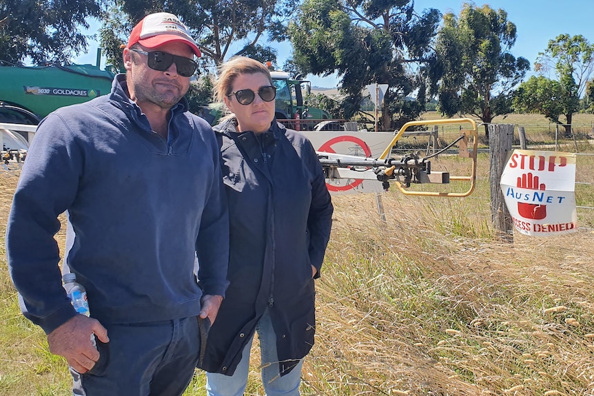 A man and a woman, looking angry as they stand in a paddock.