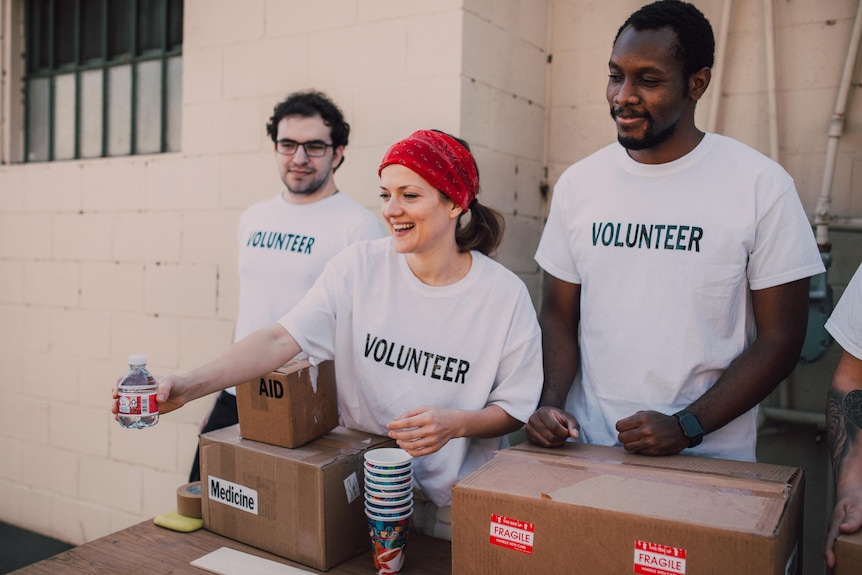 Three volunteers hand out assistance at a help desk.