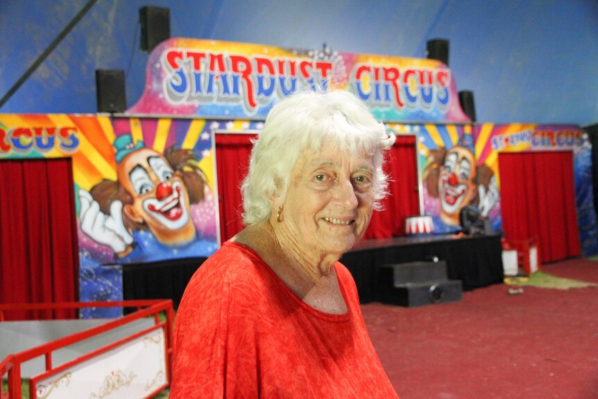 A woman wearing a red shirt stands in a circus ring