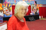 A woman wearing a red shirt stands in a circus ring