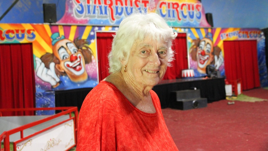 A woman wearing a red shirt stands in a circus ring