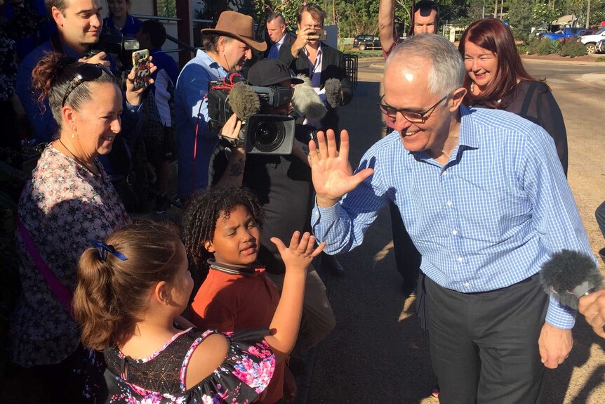 Prime Minister Malcolm Turnbull high-fiving six-year-old Yasmine Elweshahi surrounded by media.