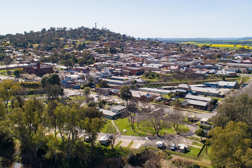 An aerial view of a small country town with yellow canola fields in the distance.