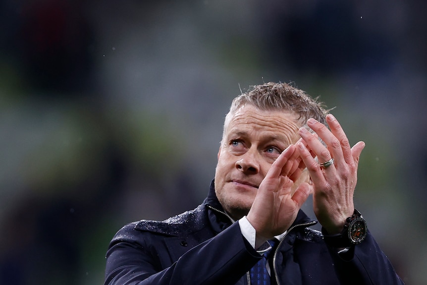 Un manager d'équipe de football en manteau applaudit pour remercier les fans de son équipe après une défaite en finale de la Ligue Europa. 