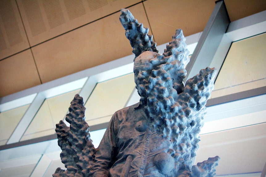 A concrete sculpture of a man blended with large coral 
