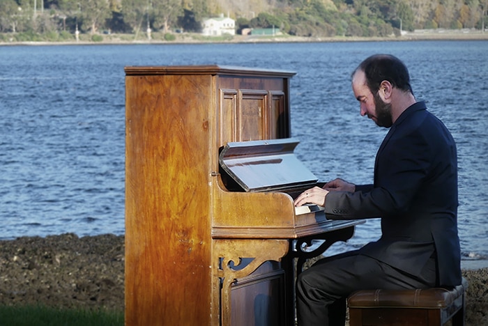 Tasmanian Kelvin Smith playing the piano next to water at Cornelian Bay, Hobart.