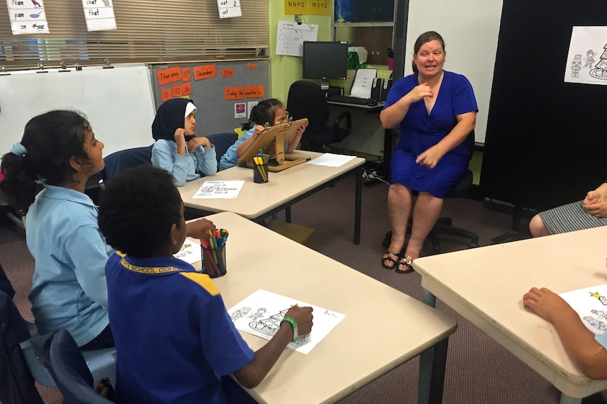 A group of children watch on as Louise de Beuzeville teaches them sign language from the centre of the room