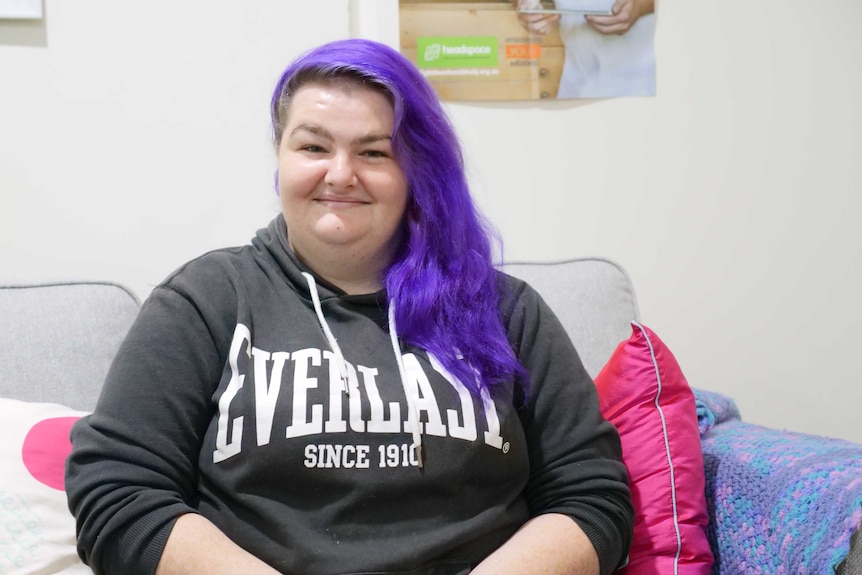 A lady sitting on a lounge smiling.