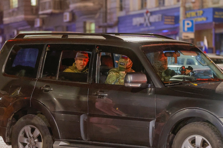 Yevgeny Prigozhin is seen through an open window sitting in teh back of a black four-wheel-drive