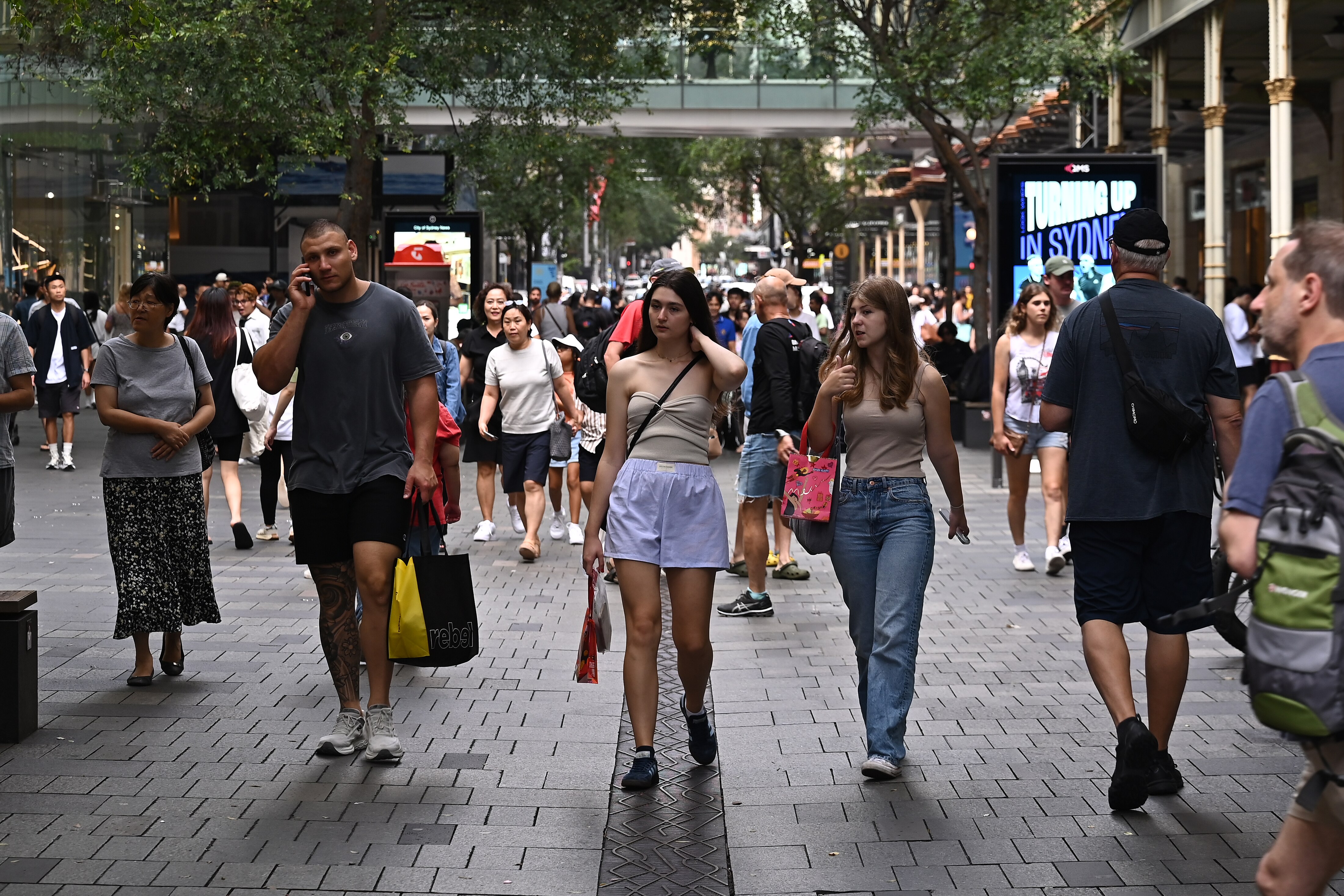 Shoppers walk down an outdoor mall.