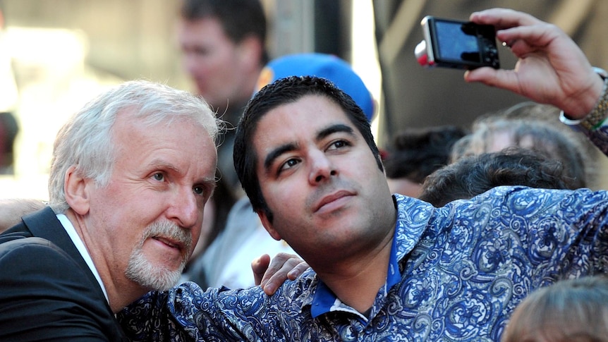 James Cameron on the red carpet with a fan.