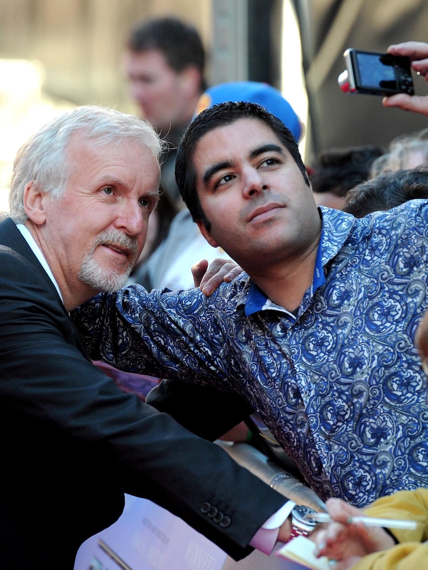 James Cameron on the red carpet with a fan.
