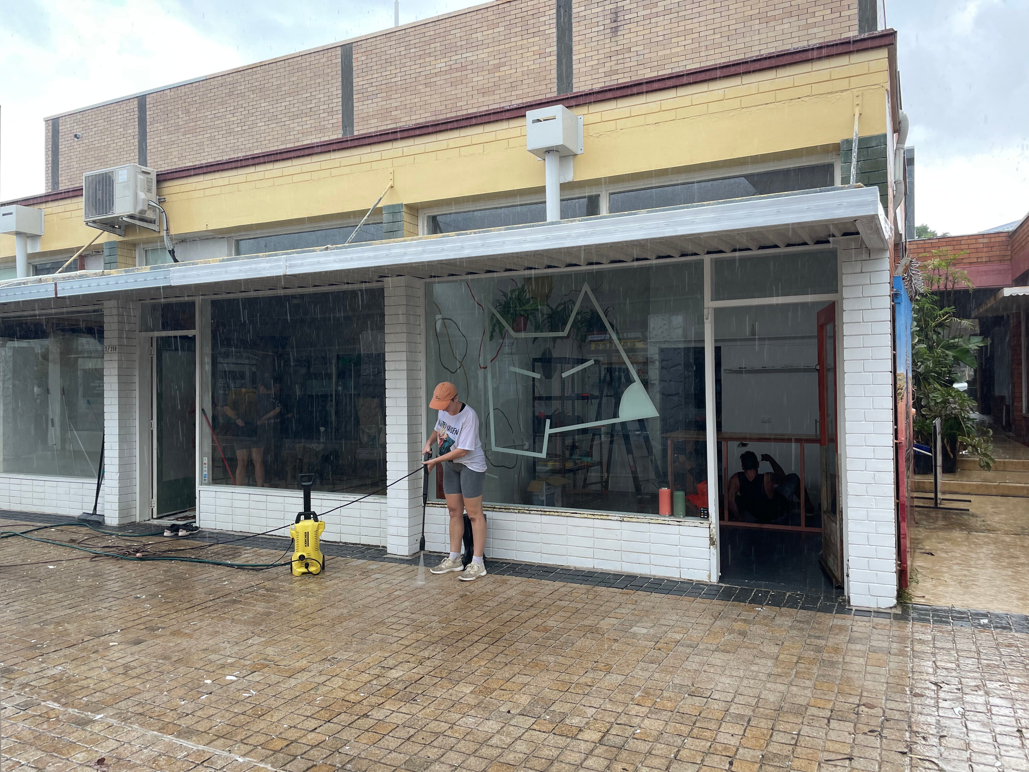 Women hoses out front of a shop 