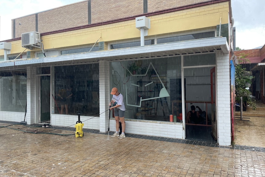 Women hoses out front of a shop 