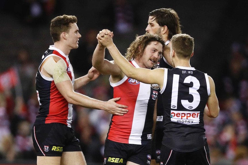 Three Saints players congratulate a smiling Jack Steven with high-fives and pats on the back.