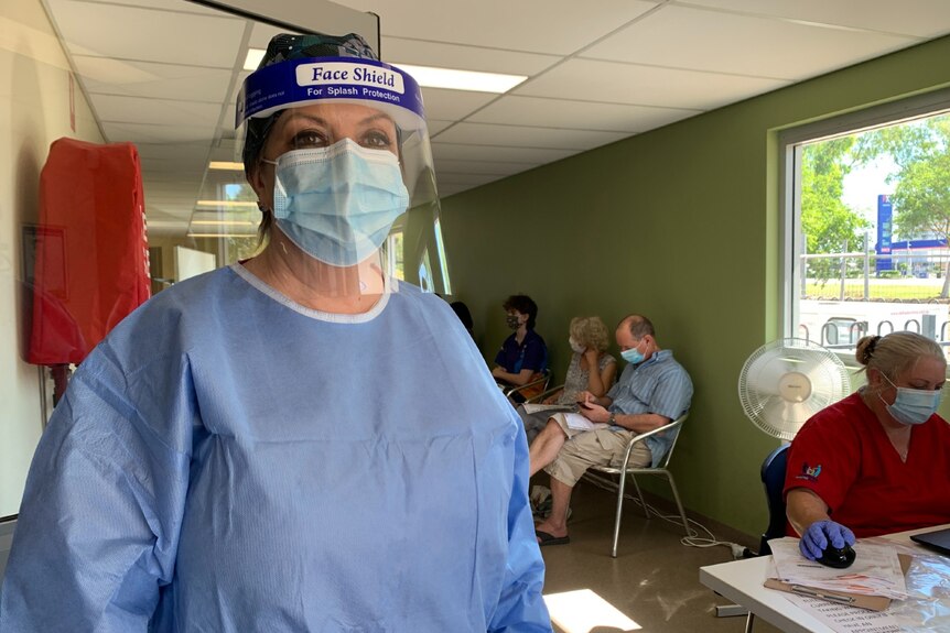 The CEO of a clinic stands indoors in full protective gear.