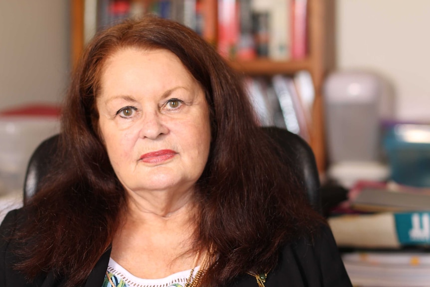 Veteran consumer advocate, Denise Brailey, sitting in office in front of book case