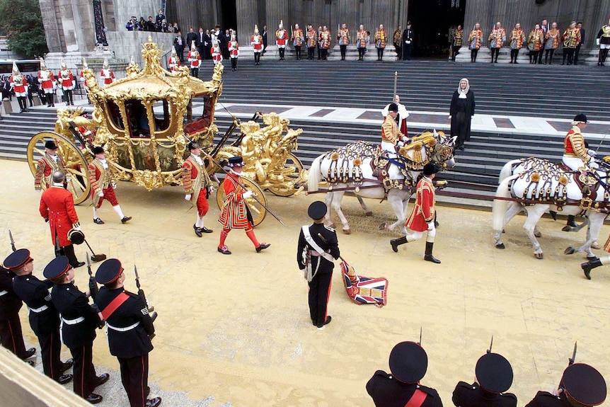 A golden coach pulled by white horses pulls up at St Pauls Cathedral