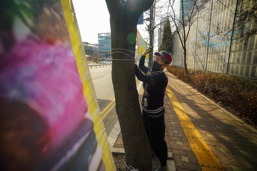 A Korea woman stringing up a banner between two trees 