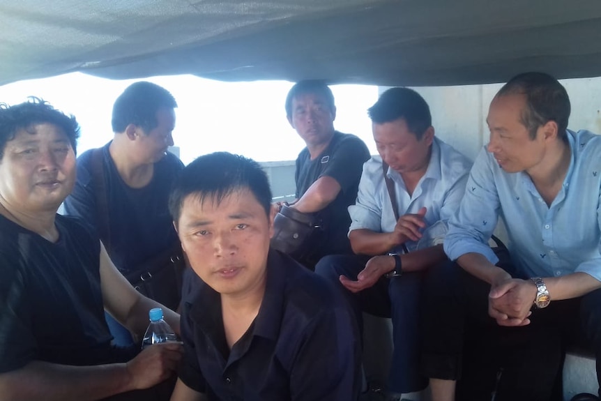 Six men look at a camera on a boat.