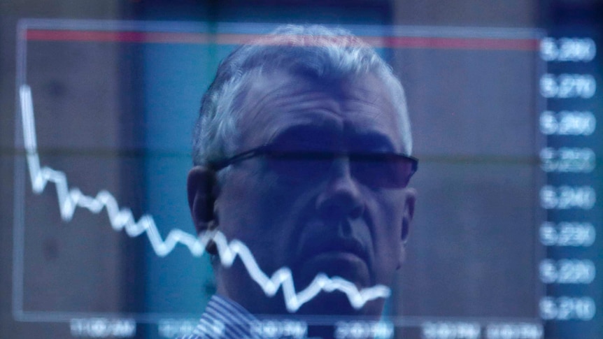 An office worker is reflected in the window of the ASX building