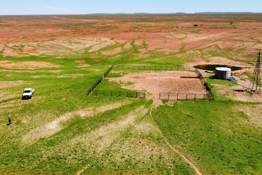 An aerial view of paddocks with greenery spreading through dry paddocks