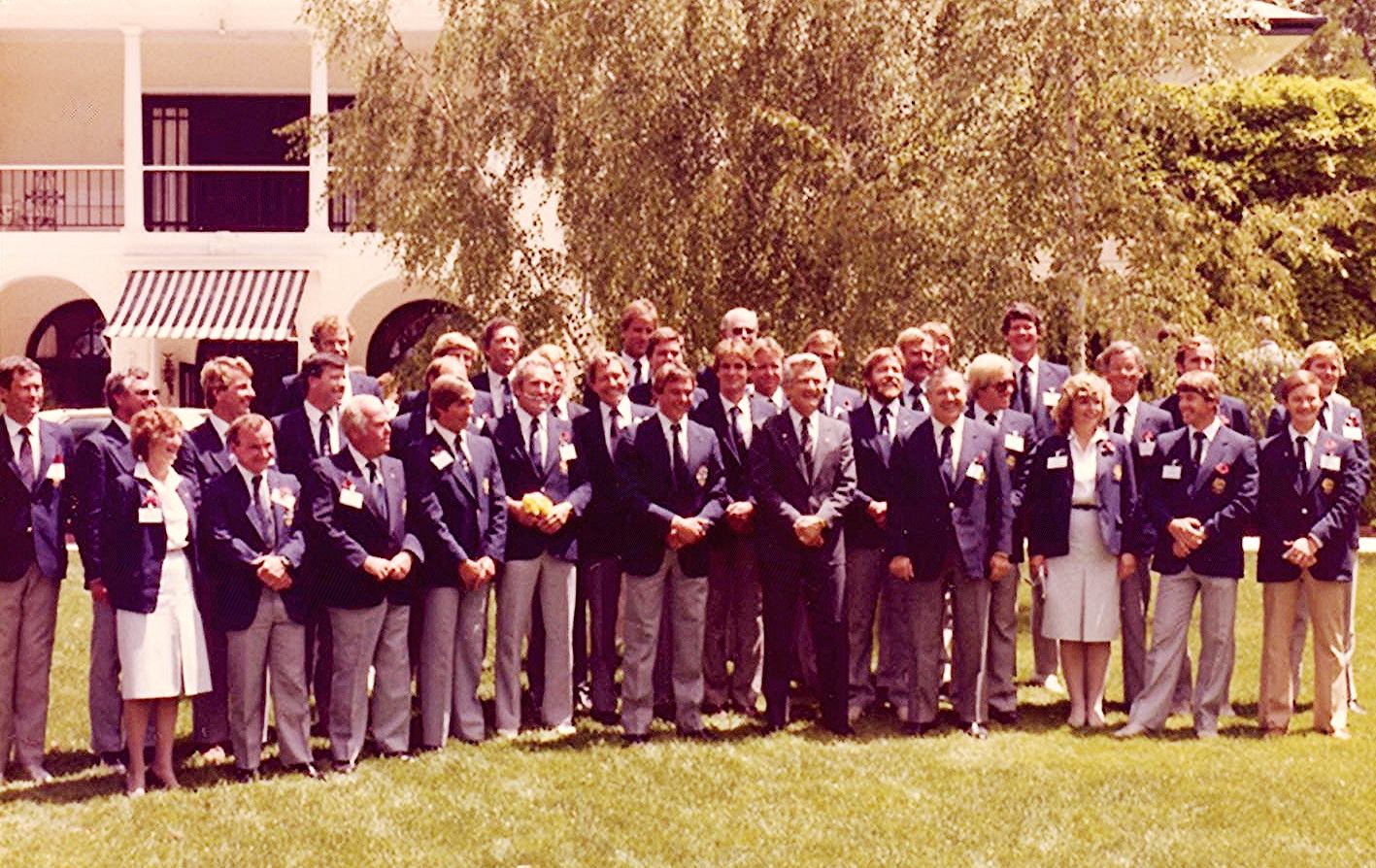 A group of smiling people in matching blazers stand on a lawn. Former prime minister Bob Hawke stands at the centre.