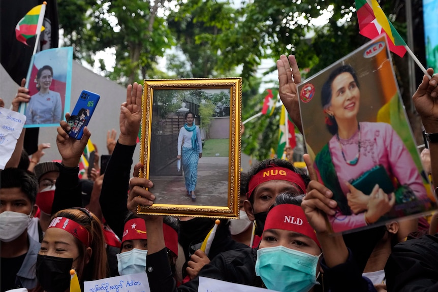 Myanmar protesters with NLD headbands holding Aung San Suu Kyi portraits