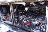 Image shows the burnt remnants of a bus and the luggage it was carrying