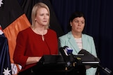 Nicole Manison and Natasha Fyles stand side-by-side in front of a number of media microphones