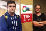 Two young men pose for the camera besides an Opal card post.