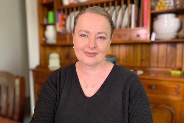 A woman sits at her table smiling at the camera