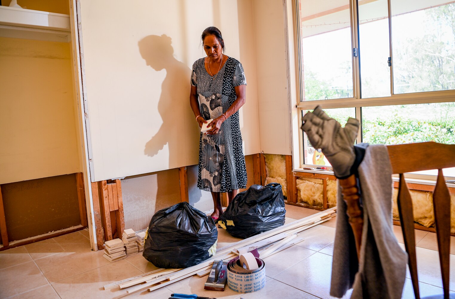 Rozeleen Kumar standing in a flood-damaged room in her home.