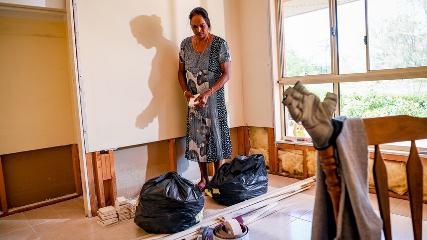 Rozeleen Kumar standing in a flood-damaged room in her home.