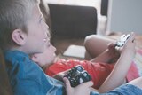 A young boy and a girl play video games while sitting on a couch, for a story about microtransactions.