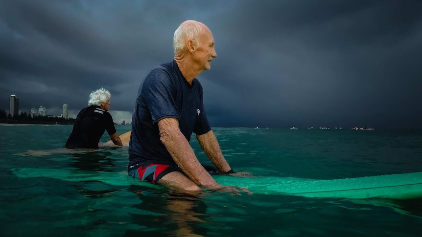 Surfer Des Salmon sitting on his board.