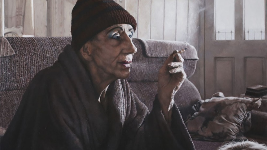 A portrait of a man sitting in his lounge room smoking and wearing a beanie. The work is titled Just an Old Drag Queen.