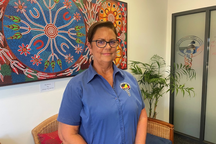 Lorraine Anderson stands in front of the painting and smiles.