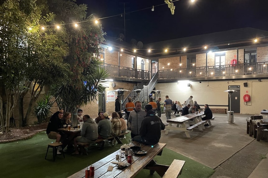  A beer garden with people sitting at tables and fairy lights strung up