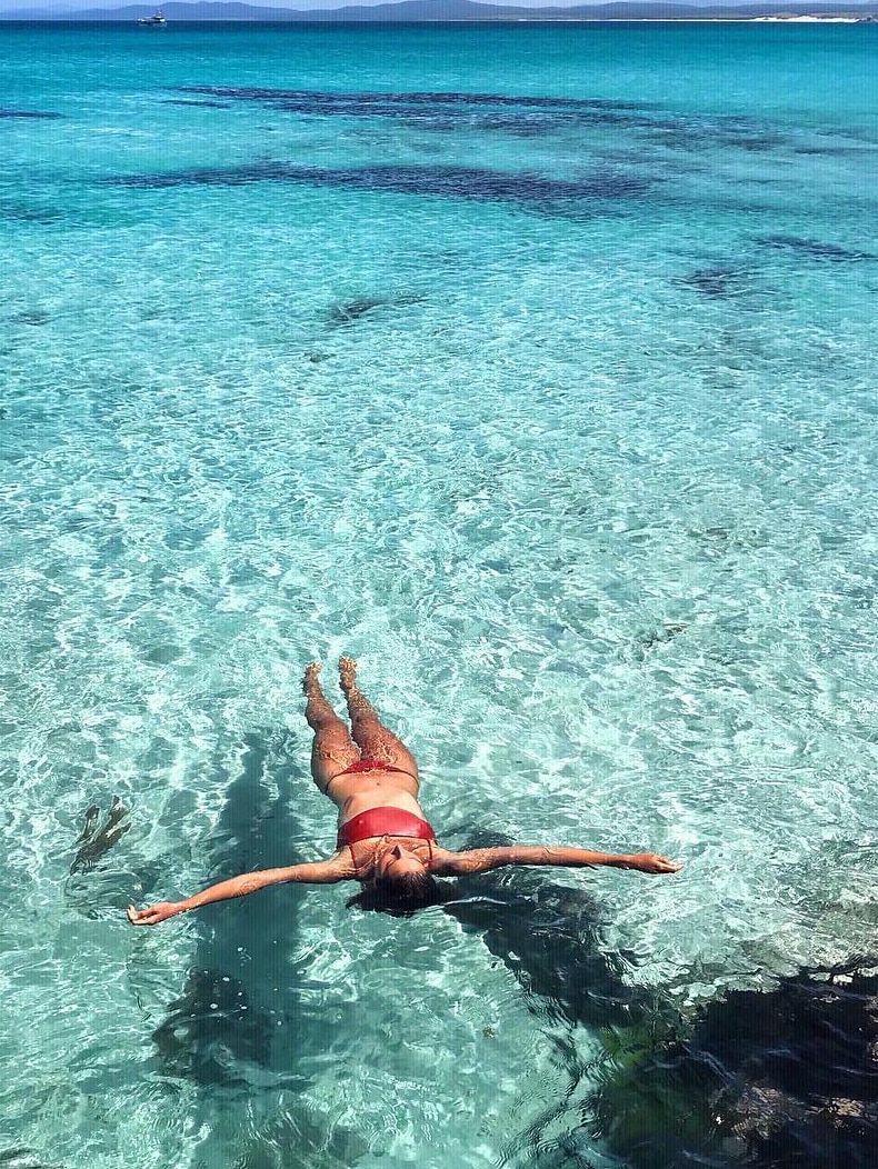 Woman lying in water at Bay of Fires, Tasmania