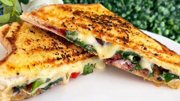 A jaffle sliced in half, oozing cheese.