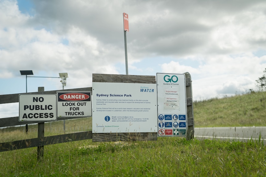 Several signs stuck to the side of a wooden fence.