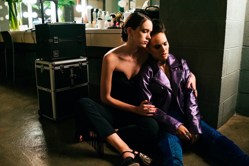 Colour still of Stacy Martin embracing an upset Natalie Portman in 2018 film Vox Lux.