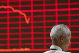 Man in front of electronic board showing stock prices in China