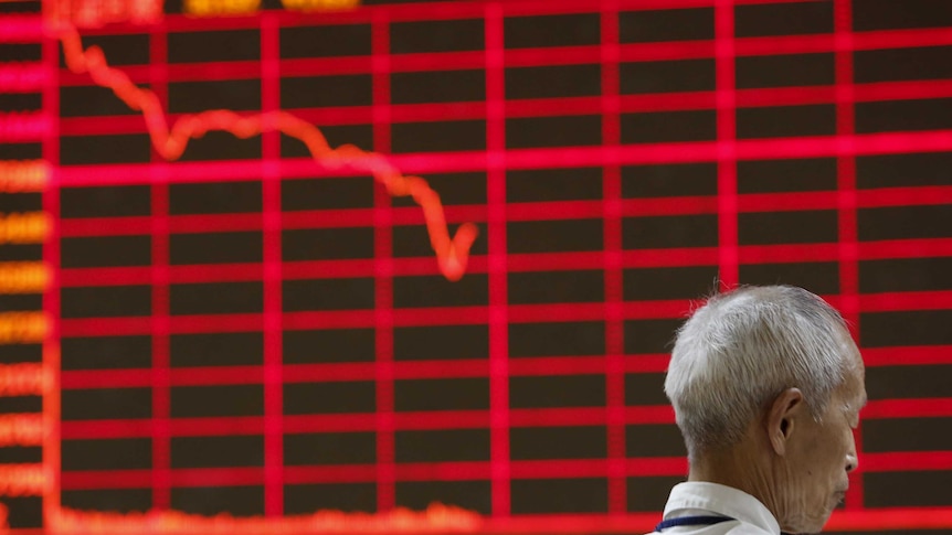 Man in front of electronic board showing stock prices in China