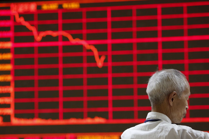 Man in front of electronic board showing stock prices in China