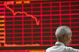 Man in front of electronic stock market board