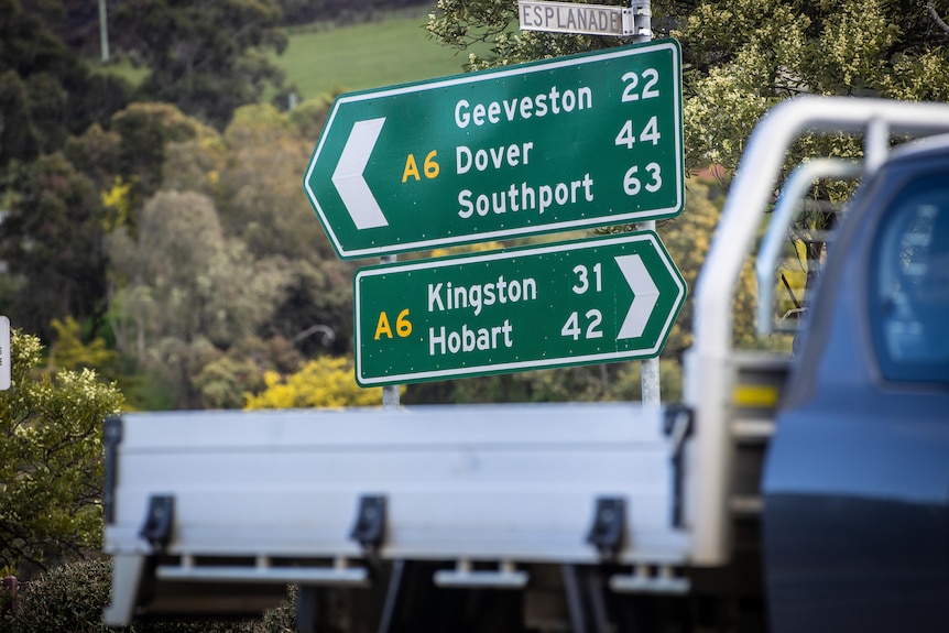 Road sign in rural town showing distances to other locations.