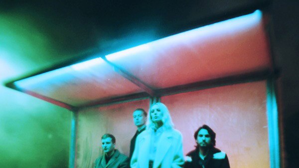 Photograph of Wolf Alice band sitting at a bus stop.