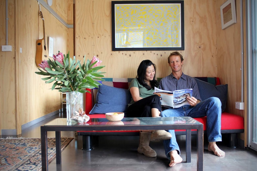 Andy Lemann and his partner Cintia Yamane sit on their couch.